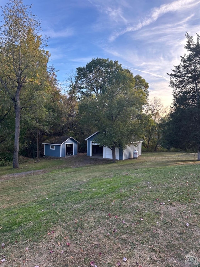 yard at dusk with a garage and an outbuilding