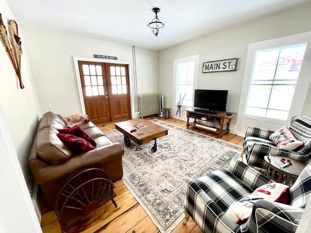 living room with french doors, light wood-type flooring, plenty of natural light, and radiator