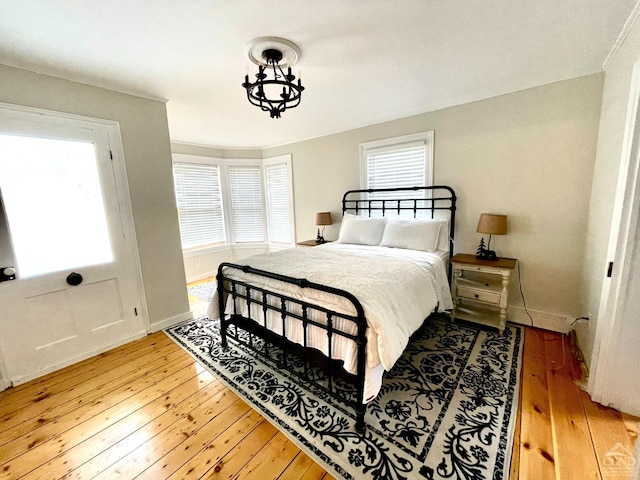 bedroom with multiple windows, wood-type flooring, and a notable chandelier