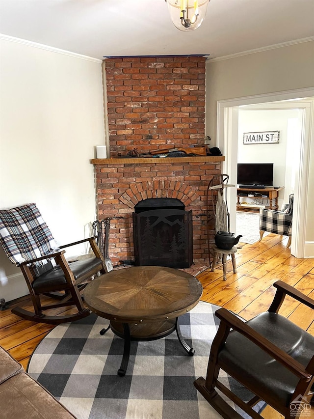 living room with hardwood / wood-style floors, crown molding, and a brick fireplace