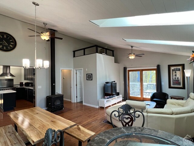 living room with a wood stove, french doors, dark wood-type flooring, vaulted ceiling with skylight, and ceiling fan with notable chandelier