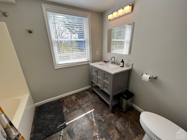 bathroom with vanity, a tub to relax in, and toilet