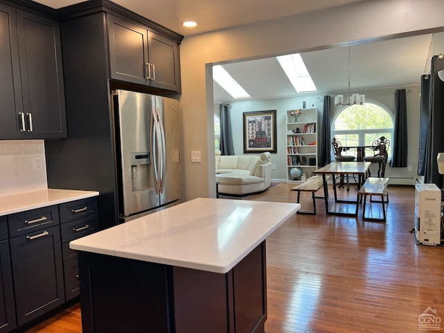 kitchen with hardwood / wood-style floors, pendant lighting, an inviting chandelier, stainless steel fridge with ice dispenser, and a center island