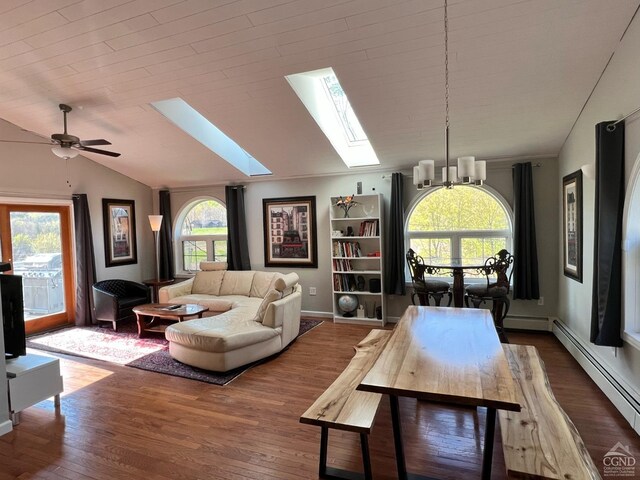 living room featuring baseboard heating, dark hardwood / wood-style flooring, vaulted ceiling with skylight, and ceiling fan with notable chandelier