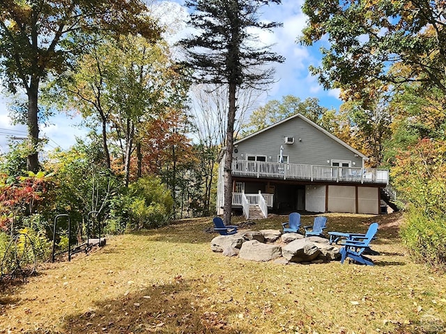 rear view of property featuring a lawn, a wooden deck, and a fire pit