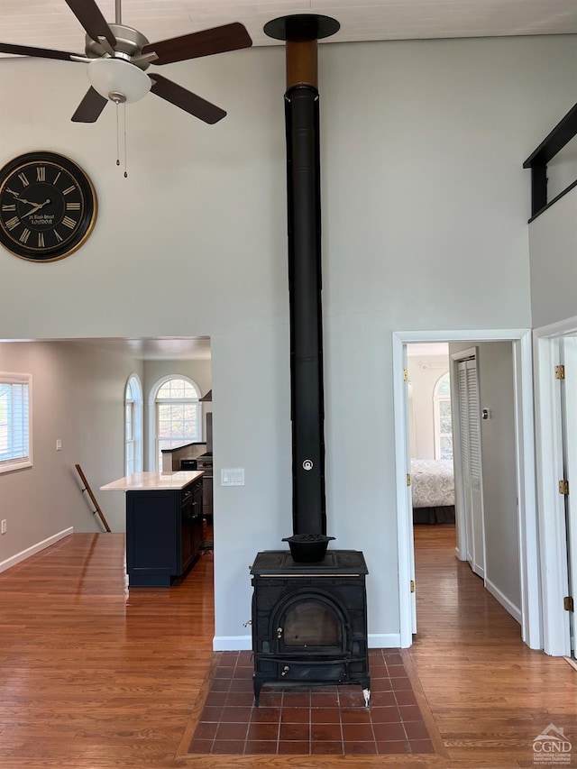 interior details with ceiling fan, wood-type flooring, and a wood stove