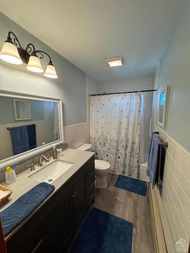 full bathroom featuring hardwood / wood-style floors, toilet, shower / bath combo with shower curtain, vanity, and tile walls