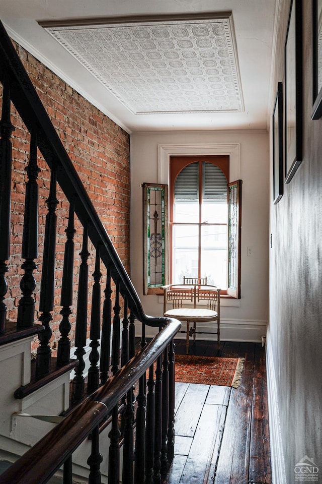 stairs with an ornate ceiling, wood-type flooring, baseboards, and brick wall