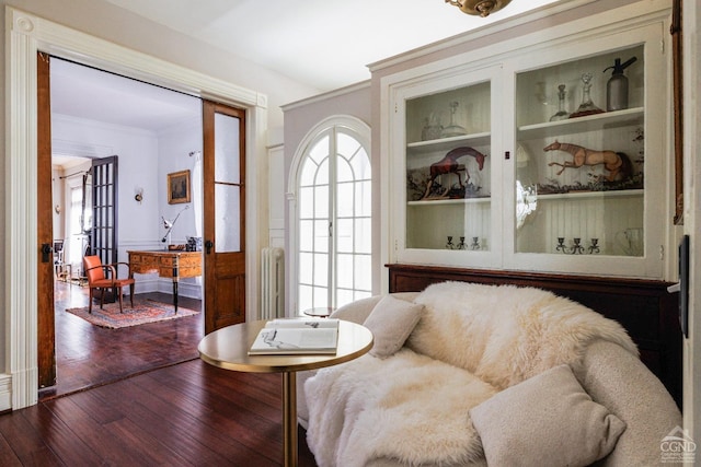 living area featuring ornamental molding, dark wood finished floors, and built in shelves