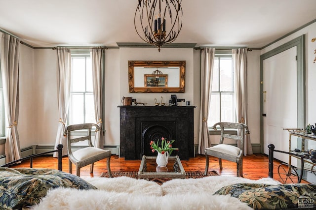 living area with a healthy amount of sunlight, a fireplace, baseboard heating, and wood finished floors