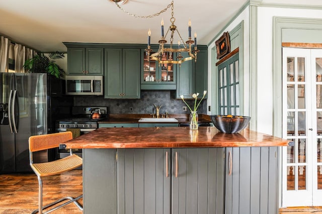 kitchen featuring butcher block counters, green cabinets, appliances with stainless steel finishes, a sink, and wood finished floors