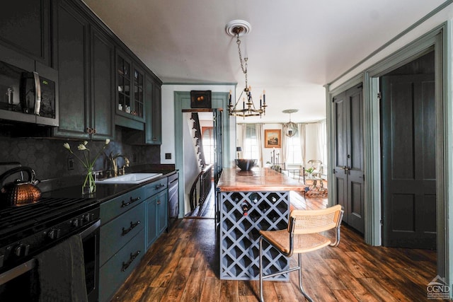 kitchen featuring dark wood finished floors, backsplash, appliances with stainless steel finishes, glass insert cabinets, and a sink