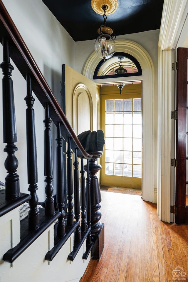 foyer entrance with stairway, a chandelier, and wood finished floors