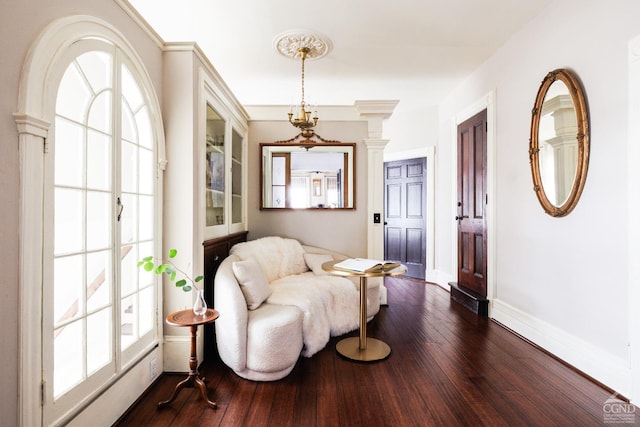 living area with dark wood-style floors, decorative columns, and baseboards