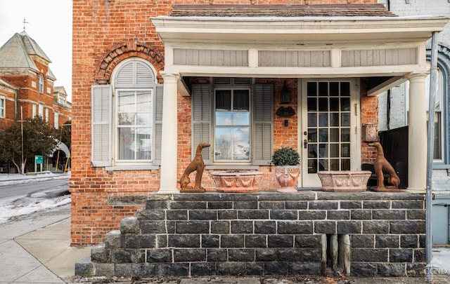 entrance to property with covered porch and brick siding