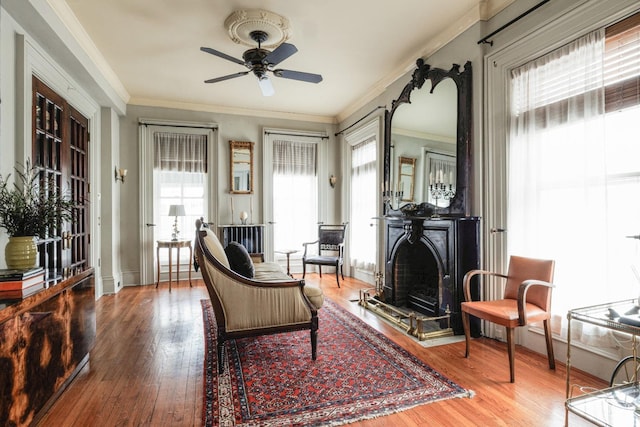 sitting room with a healthy amount of sunlight, crown molding, and wood finished floors