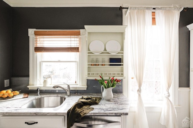 kitchen with light stone counters, white cabinets, and a sink