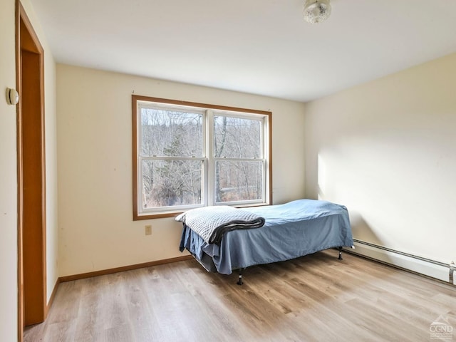 bedroom with light hardwood / wood-style floors and baseboard heating