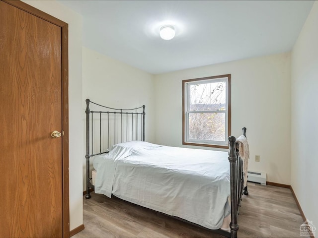 bedroom featuring light hardwood / wood-style floors and a baseboard heating unit