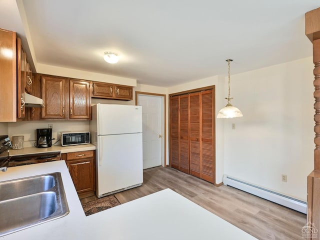 kitchen with sink, white refrigerator, decorative light fixtures, a baseboard radiator, and hardwood / wood-style floors