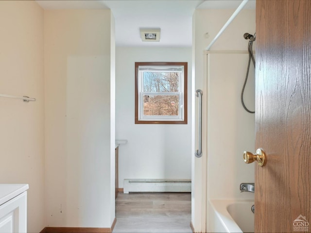 bathroom with  shower combination, hardwood / wood-style floors, vanity, and a baseboard heating unit