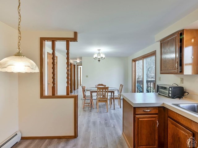 kitchen with pendant lighting, an inviting chandelier, light hardwood / wood-style floors, and a baseboard heating unit