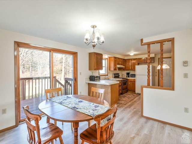 dining space with sink, light hardwood / wood-style flooring, a healthy amount of sunlight, and an inviting chandelier