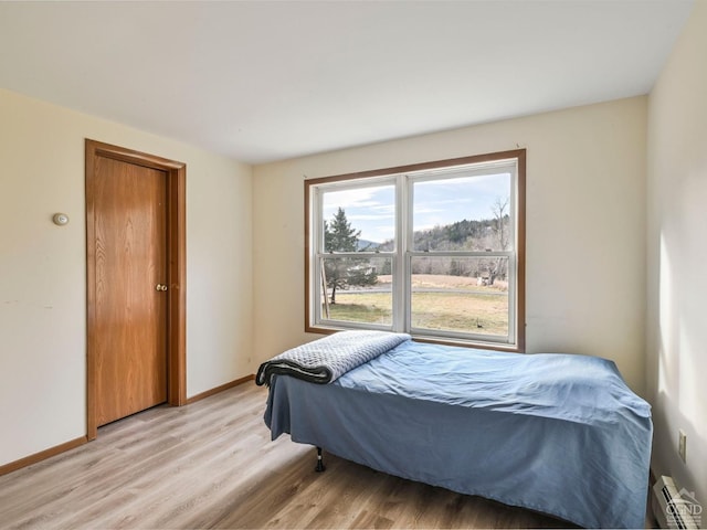 bedroom featuring light wood-type flooring and a baseboard radiator