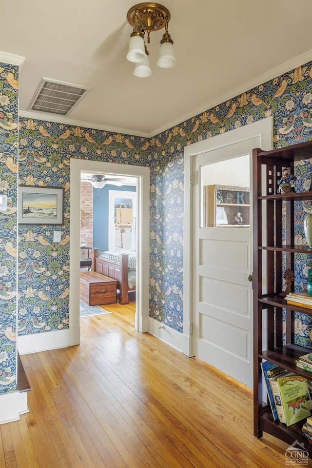 interior space with baseboards, wood finished floors, visible vents, and wallpapered walls