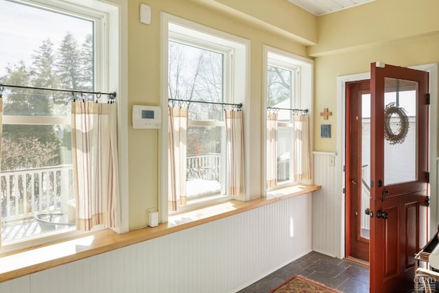 entryway with wainscoting and stone tile floors