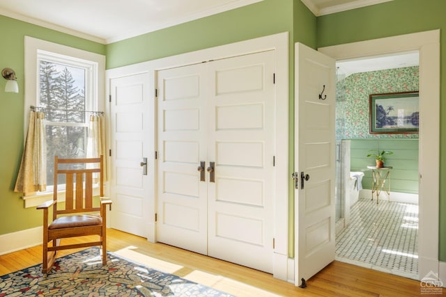 entrance foyer featuring light wood finished floors, baseboards, ornamental molding, and wallpapered walls