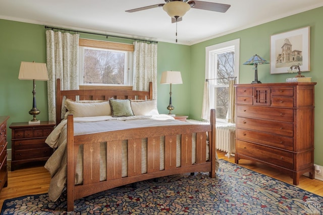 bedroom featuring radiator, crown molding, ceiling fan, and wood finished floors