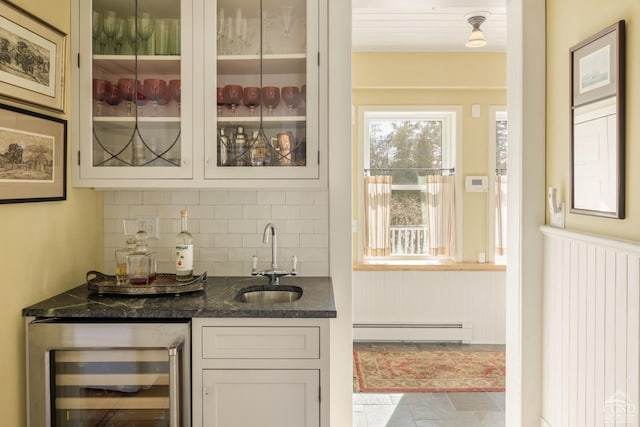 bar with wine cooler, indoor wet bar, tasteful backsplash, a baseboard heating unit, and a sink