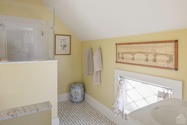 full bath featuring vaulted ceiling and baseboards