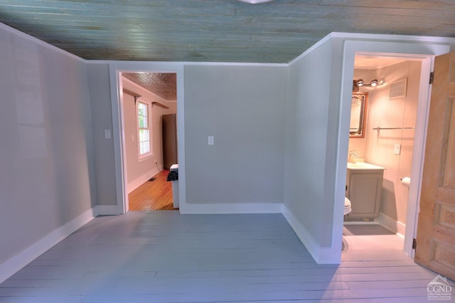 hallway with light hardwood / wood-style floors, wood ceiling, and crown molding