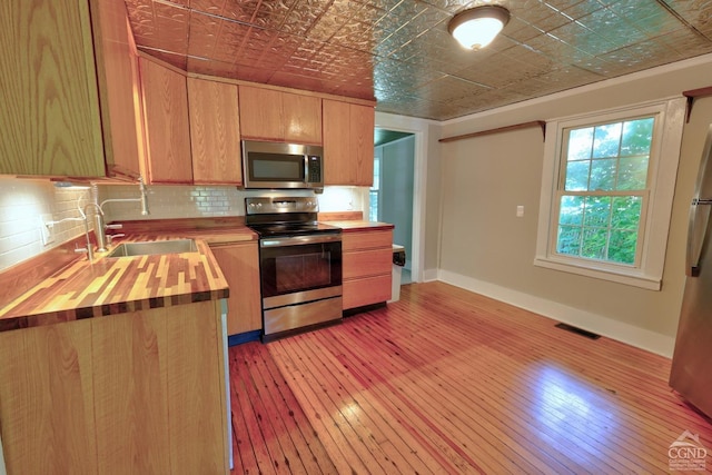 kitchen featuring wooden counters, stainless steel appliances, light hardwood / wood-style flooring, and sink