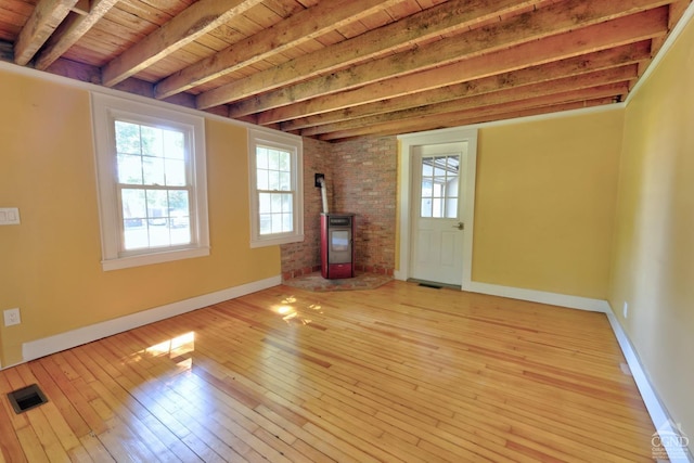 unfurnished living room with wood-type flooring, a wood stove, wooden ceiling, and beam ceiling