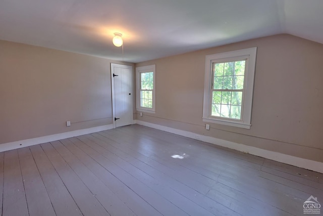 unfurnished room with plenty of natural light, vaulted ceiling, and light hardwood / wood-style flooring