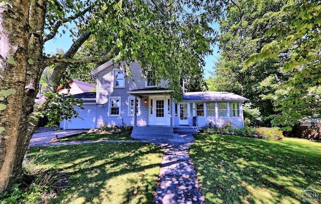 view of front of property with a sunroom, a front yard, and a garage