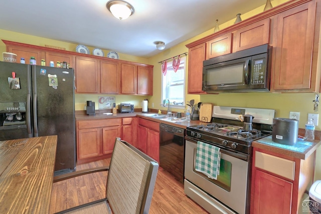 kitchen featuring black appliances, light wood-type flooring, and sink