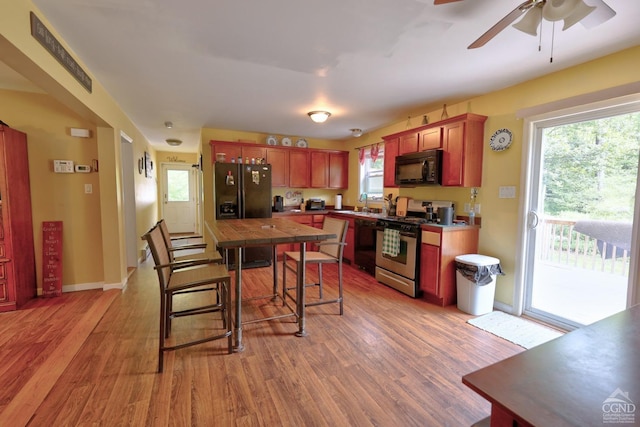 kitchen featuring black appliances, plenty of natural light, and light hardwood / wood-style flooring