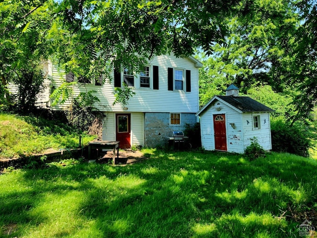 rear view of house with an outbuilding and a yard