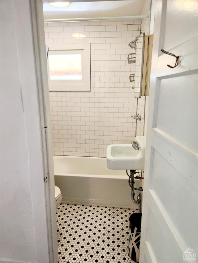 full bathroom featuring tile patterned flooring, toilet, tiled shower / bath, and sink