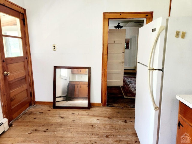 kitchen with light hardwood / wood-style flooring, white fridge, and a baseboard radiator