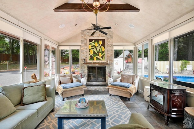 sunroom / solarium featuring vaulted ceiling with beams, ceiling fan, and a fireplace