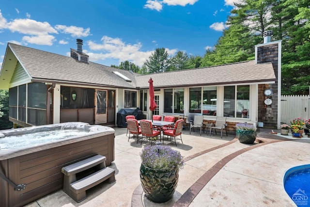 rear view of property with a hot tub, a patio area, and a sunroom