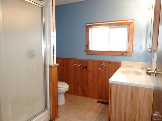 bathroom featuring vanity, tile patterned floors, wooden walls, toilet, and an enclosed shower