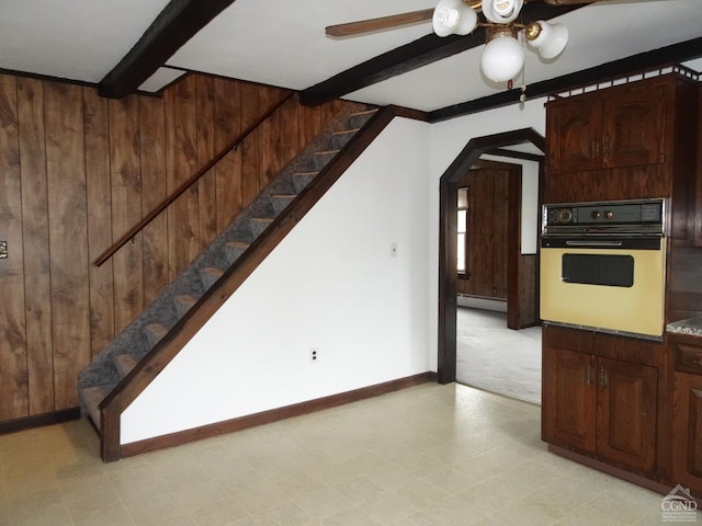 kitchen featuring wall oven, ceiling fan, a baseboard heating unit, beam ceiling, and wood walls