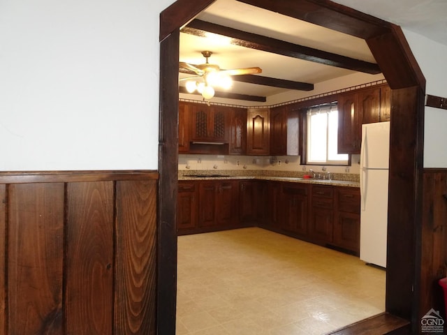 kitchen with light stone countertops, dark brown cabinets, ceiling fan, beamed ceiling, and white fridge