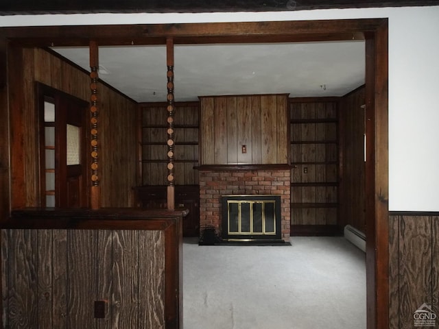 unfurnished living room featuring wood walls, carpet floors, a baseboard radiator, and a brick fireplace